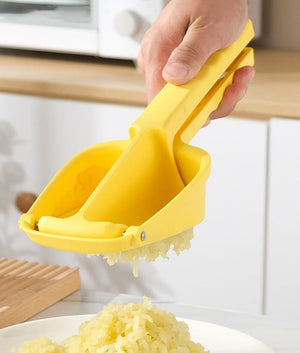 Yellow potato ricer being used to mash potatoes on a kitchen counter.